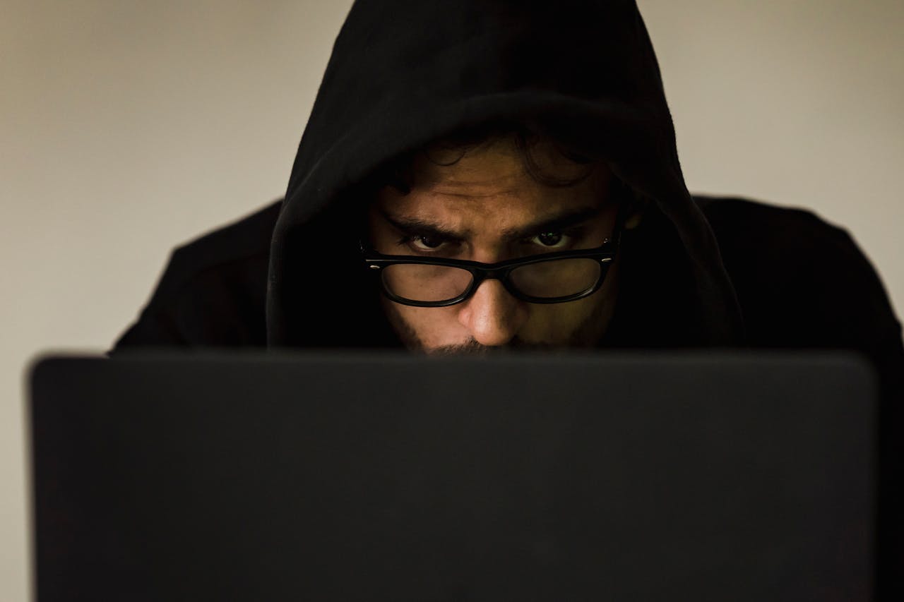 hero-img-01 Serious young male programmer wearing black hoodie browsing netbook and hacking software in studio